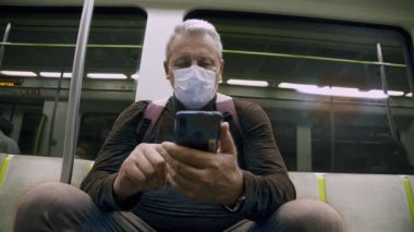 Koruyucu maskeli yaşlı bir adam metroya biniyor.