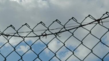 Bir yolcu uçağı, gökyüzünün arka planına karşı irtifa kazanıyor ve bir tel örgü, havaalanı çitlerinin metal ızgarasından vuruluyor.