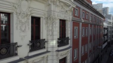 MADRID, SPAIN - 27, 2021: Metropolis Binası duvarı boyunca ustaca yapılmış sıva işçiliği ve heykellerle uçan helikopter. Yerleşim alanları ve bulutlu gökyüzü olan Madrid hava sahnesini takip ediyoruz.