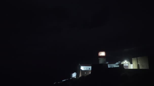 Majákové světlo na obloze osvětlující černou noční oblohu a okolní domy