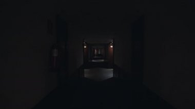 Karanlık koridorda yürürken çekilen görüntü ve sonra ışıklar yanıyor. Beyaz duvarları ve karanlık ahşap kapıları olan boş bir otel koridoru. Konforlu konaklama