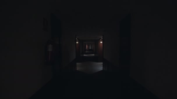 拍摄的观点是沿着黑暗的大厅走着 然后灯就亮了 空荡荡的酒店走廊 白色的墙壁和漆黑的木门 舒适的住宿 — 图库视频影像