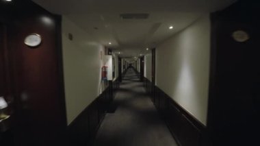 Steadicam otelin uzun koridorunda bir yürüyüşü filme aldı. Gri duvar kağıdı ve büyük kahverengi ahşap kapılar.