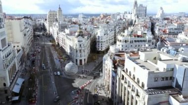 MADRID, SPAIN - 27 Kasım 2021: Alcala ve Gran Via caddeleriyle güneşli bir gün. Metropolis Binası ve Edificio Çimenliği 'nin üzerinde uçuyor.