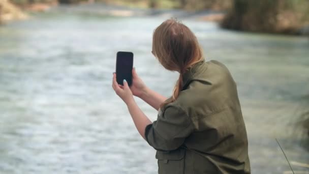 Молодая Блондинка Расслабляется Реки Фотографирует Природу Затем Просматривает Фотографии Мобильном — стоковое видео