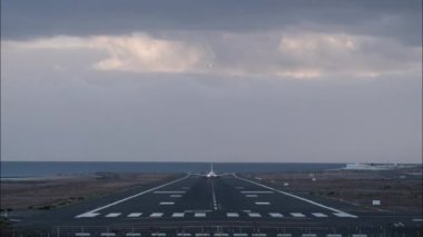 Zaman aşımı, cephe manzarası. Akşamleyin havalanan ve inen uçak, deniz kıyısından başlayan ışıklı bir piste iniyor.