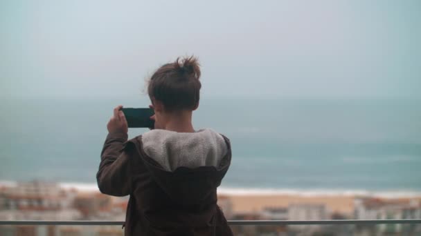 Chłopiec Podróżnik Robi Zdjęcia Smartfonem Balkonu Scena Oceaniczna Linia Brzegowa — Wideo stockowe