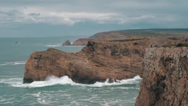 ポルトガルのセントビンセント岬 大西洋のサイアン波は 急な陸地の岩を粉砕します 曇りの空と海岸風景 景色を楽しむ観光客は少ない — ストック動画