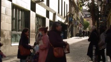 MADRID, SPAIN - 07 Mart 2022: İnsanlar dar bir şehir caddesi boyunca reklam afişlerinin asıldığı evler boyunca yürür, arabalar geçer
