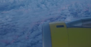 Akşam gökyüzünde kabarık bulutların üzerinde uçan bir uçağın lombozundan bir jet motoru ya da türbin görüntüsü