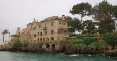 Casa de Santa Maria in Cascais, Portugal. Exterior of an ancient building on the ocean coast with scenic rocks and trees