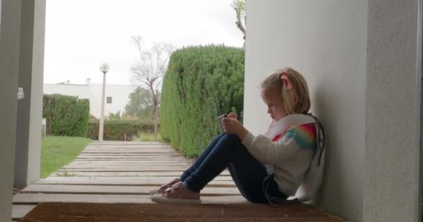 Preschooler Girl Sitting Home Front Door Using Smartphone Wooden Path — Stock videók