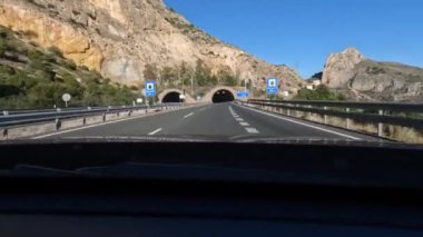 Otoyol boyunca sürüşü hızlandırılmış bir bakış açısı. Resimli manzarayı bir kenara bırakıp dağdaki tünelden geçiyor. Araba yolculuğu.