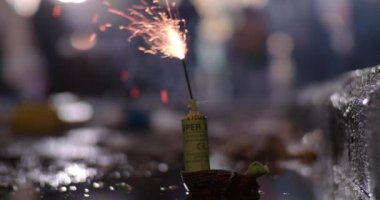 Close-up shot of a burning fuse with following bomb detonation in the puddle, explosion with water splash. Celebrating Fallas festival with pyrotechnics, Spain