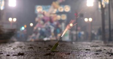 Close-up shot of burning a small bomb and following explosion in the street at night. Fireworks and firecrackers are common during Fallas celebration in Spain