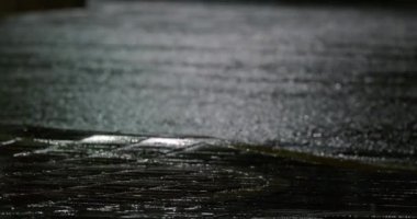 It is raining at night, cars are driving along the wet highway, the glare of parking lights is visible