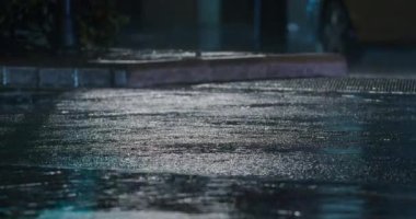 Several cars driving on the wet road and splashing puddles on the asphalt at rainy night