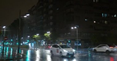 VALENCIA, İSPA - 13 Temmuz 2022: gece sokakta taşımacılık trafiği. Bardaktan boşanırcasına yağmur yağıyor ve yol ışıklarıyla parıldıyor.