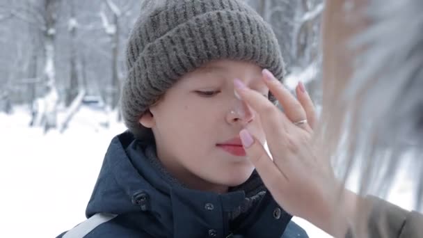 外で冬の楽しみを持つ前にクリームと母保湿の息子の顔 寒さと霜の多い天候は肌を乾燥させる — ストック動画