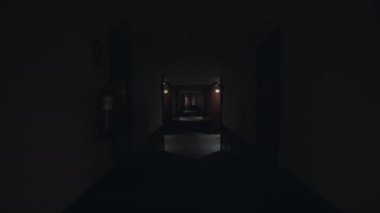 Karanlık koridorda yürürken çekilen görüntü ve sonra ışıklar yanıyor. Beyaz duvarları ve karanlık ahşap kapıları olan boş bir otel koridoru. Konforlu konaklama