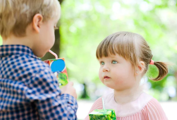 Små barn dricka juice i naturen — Stockfoto