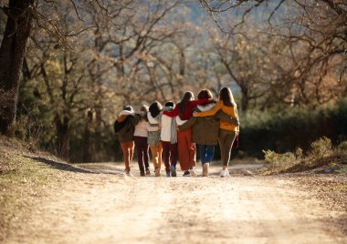 Yedi mutlu arkadaştan oluşan bir grup düz yolda yürüyor. Sonbahar mevsimi.
