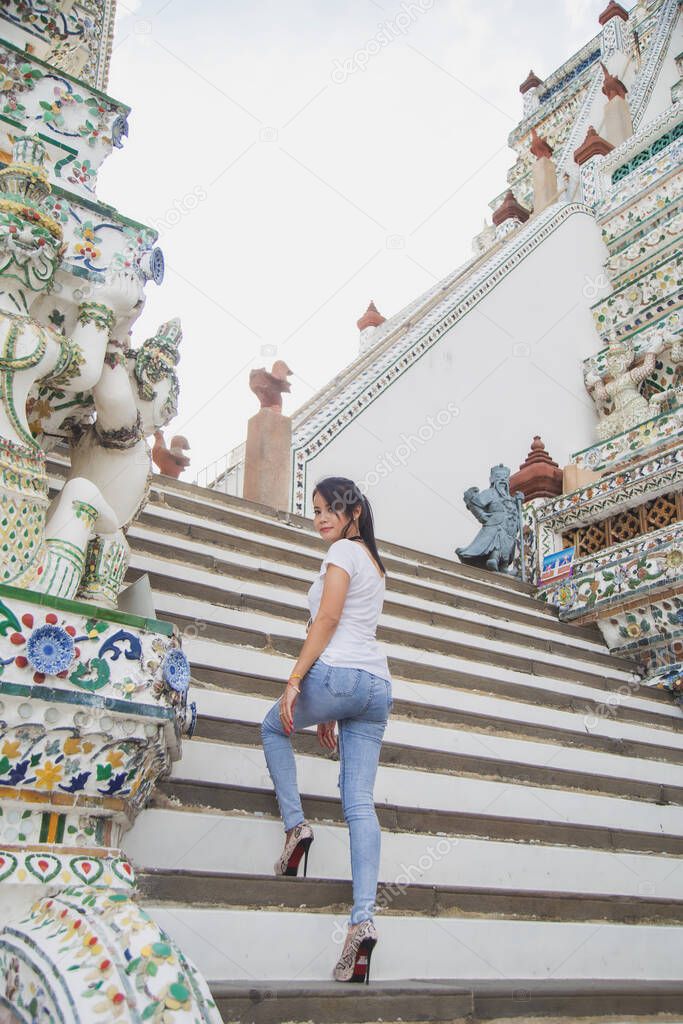 Portrait beautiful Asian woman in a white T-shirt looking at a camera at the Wat Arun temple while traveling in Thailand.