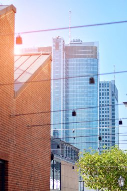 Modern şehir için ilham verici bir manzara. Cam ve metalden yapılmış binanın duvarı ağaçlara karşı. Şirket inşaatı ve ekoloji, mavi gökyüzü ve yeşil ağacı olan modern bina manzarası. Güneş ışığı