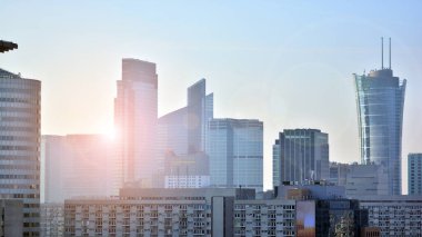 Modern şehir için ilham verici bir manzara. Cam ve metalden yapılmış binanın duvarı ağaçlara karşı. Şirket inşaatı ve ekoloji, mavi gökyüzü ve yeşil ağacı olan modern bina manzarası. Güneş ışığı