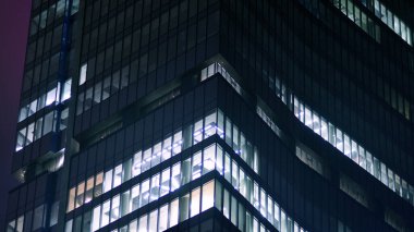 Geceleri şirket binası, iş konsepti. Camdan ofis binası. Geceleri parlayan modern gökdelen ofis pencereleri..