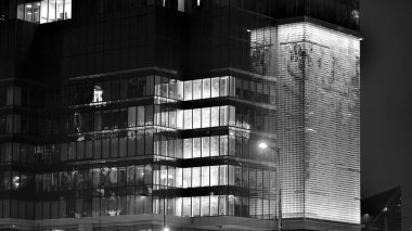 Geceleri şirket binası, iş konsepti. Camdan ofis binası. Geceleri parlayan modern gökdelen ofis pencereleri. Siyah ve beyaz.