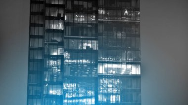 Geceleri şirket binası, iş konsepti. Camdan ofis binası. Geceleri parlayan modern gökdelen ofis pencereleri. Siyah ve beyaz.