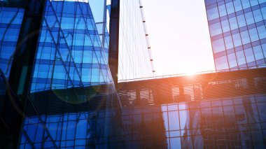 Gökyüzü arka planında cam cepheli modern ofis binası. Ofis binasının şeffaf cam duvarı ve güneş ışığı.