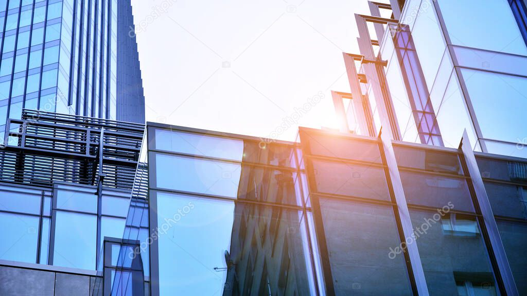 Modern office building with glass facade on a clear sky background. Transparent glass wall of office building and sunlight.