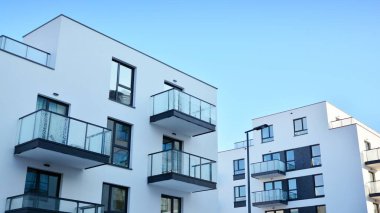 Güneşli bir günde modern bir apartman dairesi cephesi. Kocaman pencereleri ve balkonları olan modern apartmanlar..