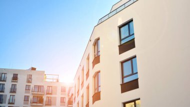 Güneşli bir günde modern bir apartman dairesi cephesi. Kocaman pencereleri ve balkonları olan modern apartmanlar..
