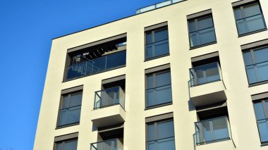 Güneşli bir günde modern bir apartman dairesi cephesi. Kocaman pencereleri ve balkonları olan modern apartmanlar..