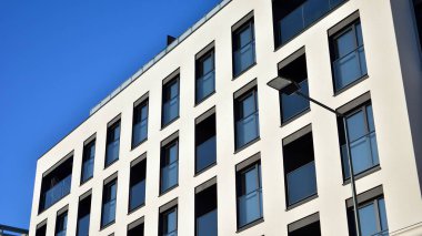 Güneşli bir günde modern bir apartman dairesi cephesi. Kocaman pencereleri ve balkonları olan modern apartmanlar..