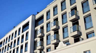 Güneşli bir günde modern bir apartman dairesi cephesi. Kocaman pencereleri ve balkonları olan modern apartmanlar..