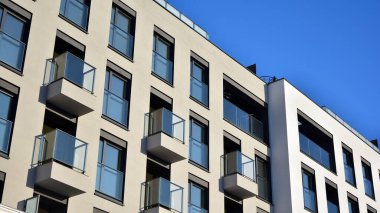 Güneşli bir günde modern bir apartman dairesi cephesi. Kocaman pencereleri ve balkonları olan modern apartmanlar..