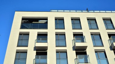 Güneşli bir günde modern bir apartman dairesi cephesi. Kocaman pencereleri ve balkonları olan modern apartmanlar..
