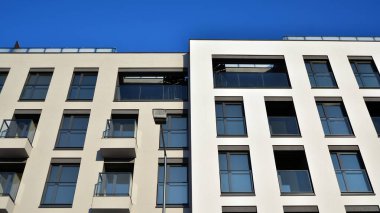 Güneşli bir günde modern bir apartman dairesi cephesi. Kocaman pencereleri ve balkonları olan modern apartmanlar..