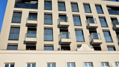 Güneşli bir günde modern bir apartman dairesi cephesi. Kocaman pencereleri ve balkonları olan modern apartmanlar..
