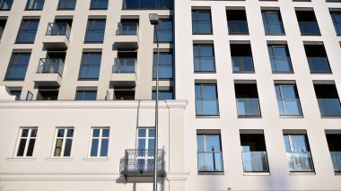 Güneşli bir günde modern bir apartman dairesi cephesi. Kocaman pencereleri ve balkonları olan modern apartmanlar..