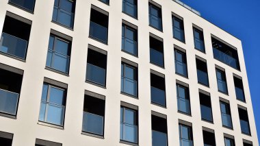 Güneşli bir günde modern bir apartman dairesi cephesi. Kocaman pencereleri ve balkonları olan modern apartmanlar..