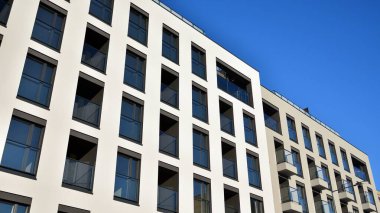 Güneşli bir günde modern bir apartman dairesi cephesi. Kocaman pencereleri ve balkonları olan modern apartmanlar..