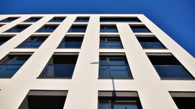 Güneşli bir günde modern bir apartman dairesi cephesi. Kocaman pencereleri ve balkonları olan modern apartmanlar..