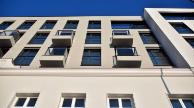 Güneşli bir günde modern bir apartman dairesi cephesi. Kocaman pencereleri ve balkonları olan modern apartmanlar..