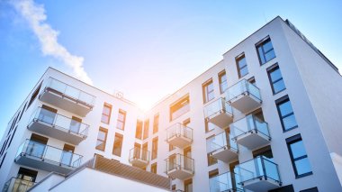 Güneşli bir günde modern bir apartman dairesi cephesi. Kocaman pencereleri ve balkonları olan modern apartmanlar..