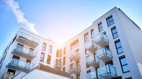 Güneşli bir günde modern bir apartman dairesi cephesi. Kocaman pencereleri ve balkonları olan modern apartmanlar..